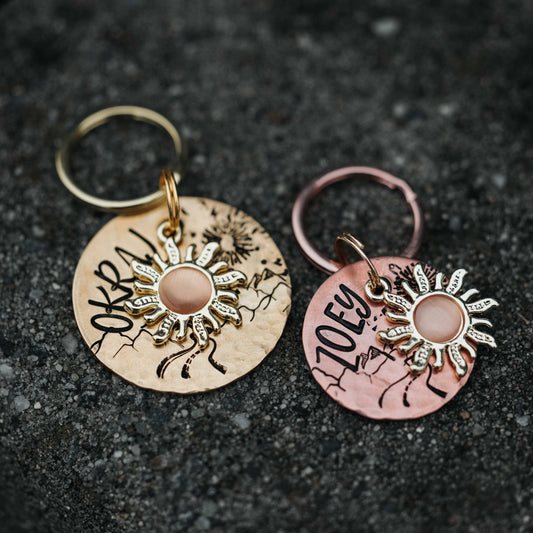 okrągła adresówka dla psa Arizona Sun z motywem gór i słońca w dwóch rozmiarach 25mm i 32mm mosiądz i miedź